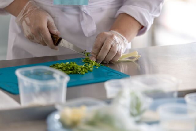 Ierburi aromatice proaspete, usturoi, lămâie și condimente așezate pe un tocător de lemn în bucătărie