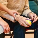 Alergător așezat pe pistă care își ține glezna dureroasă cu ambele mâini după o entorsă